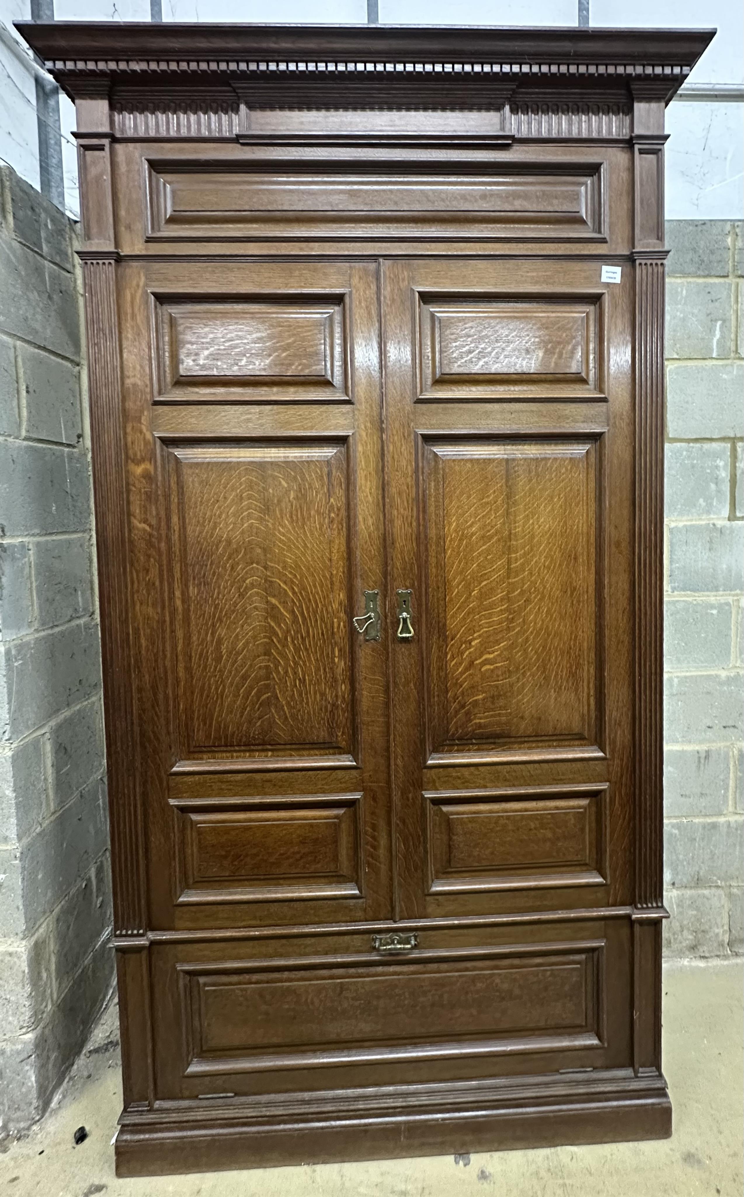 A late Victorian panelled oak wardrobe retailed by Maple & Co., width 124cm, depth 42cm, height 230cm. Condition - fair, two pieces of cornice timber missing